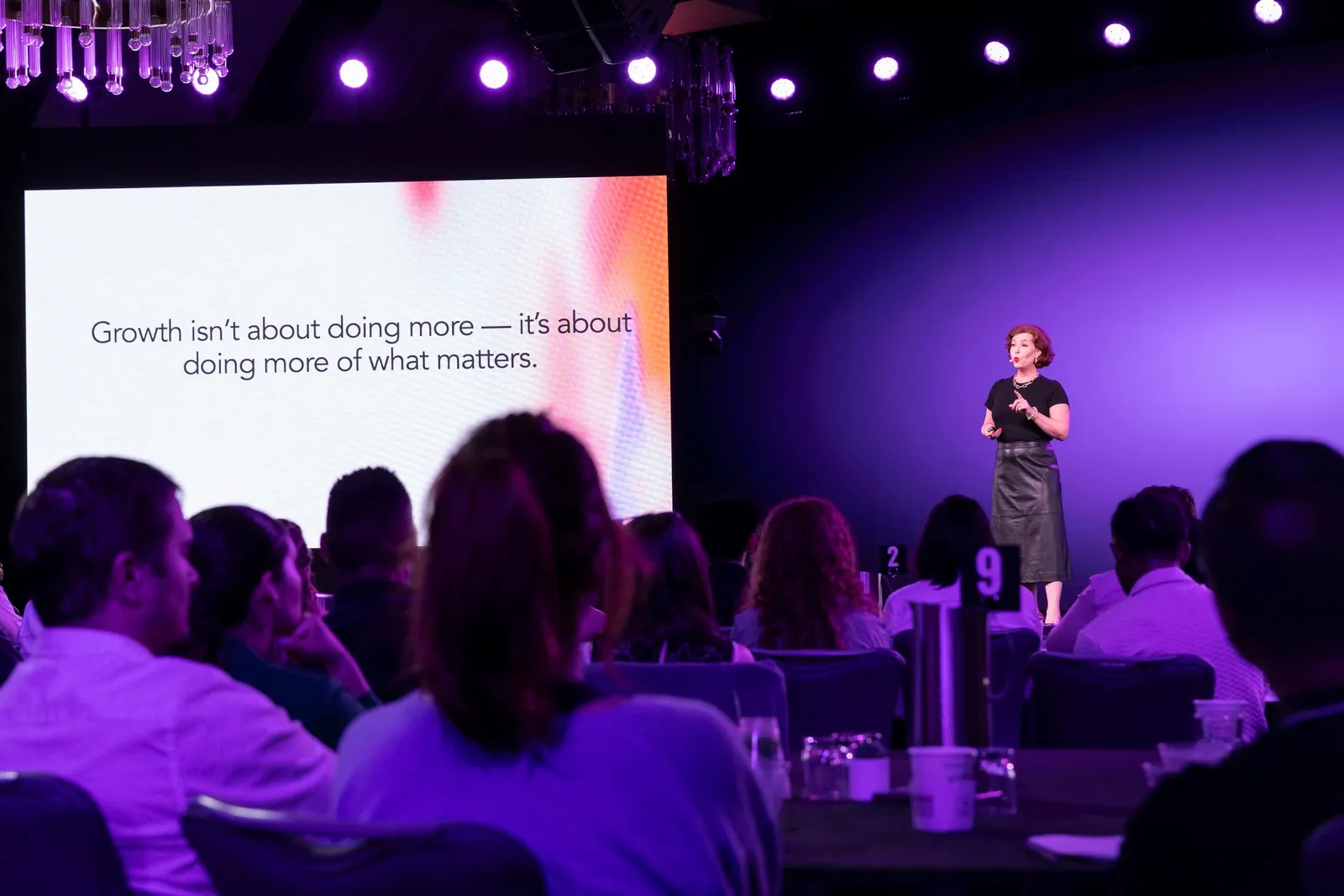 Christine DiDonato speaking to a full ballroom beside a slide reading Growth isn't about doing more